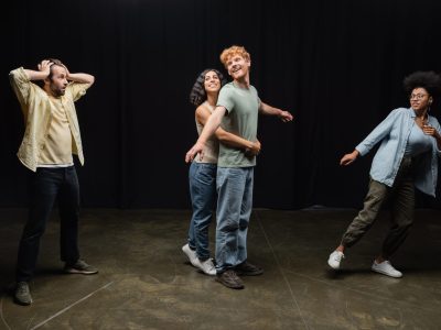 full length of emotional interracial students of acting skills school rehearsing in theater,stock image